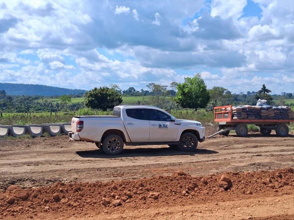 Caminhonete branca da SV Topografia e Projetos com reboque carregado em canteiro de obras